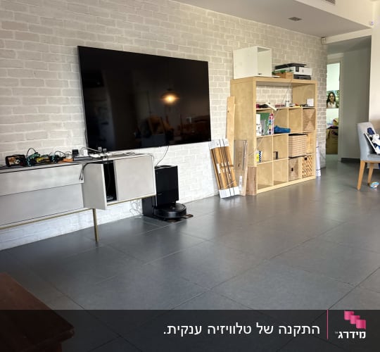 חדר מגורים עם טלוויזיה גדולה ומדפים